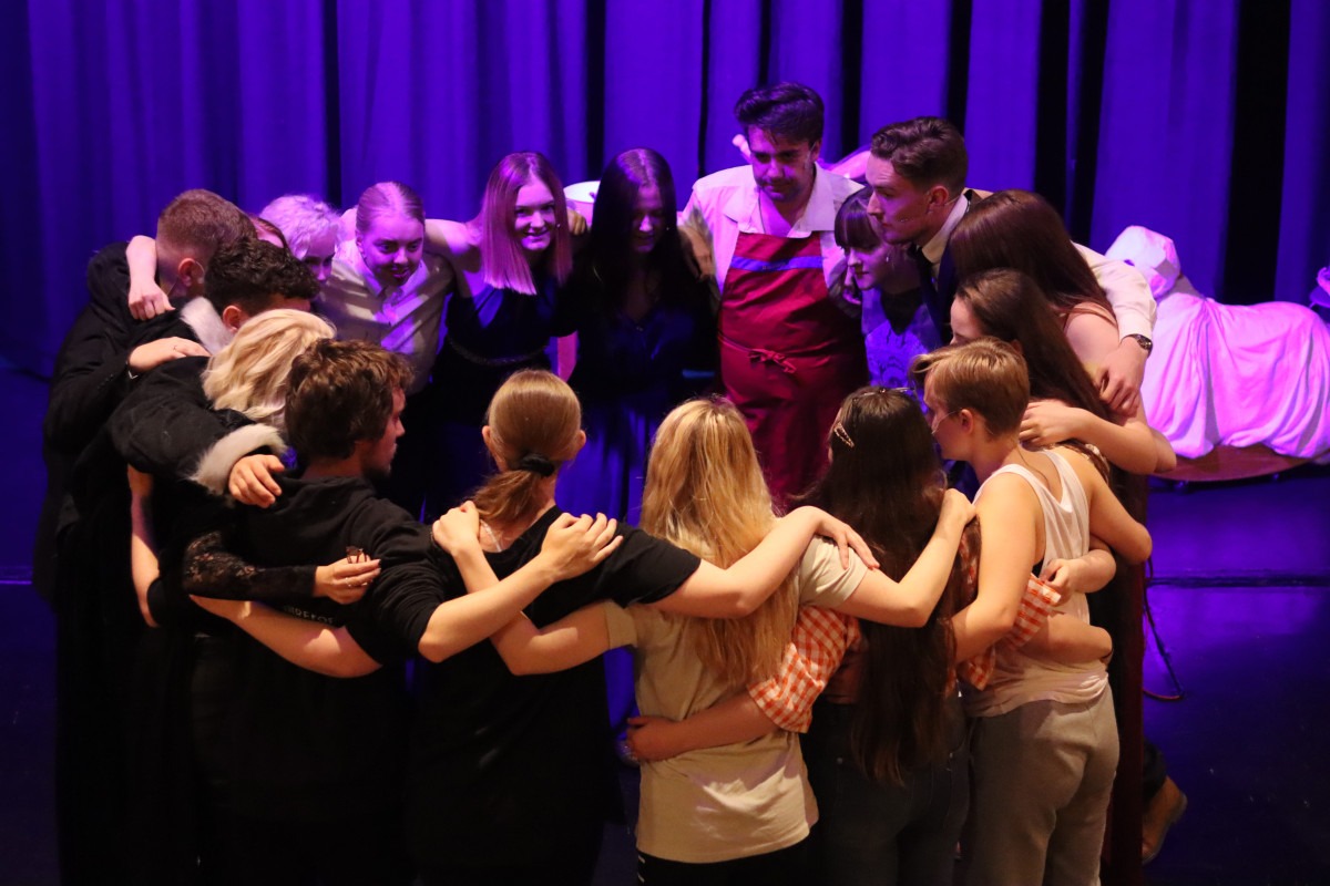 A theatre production cast huddle on-stage before a show