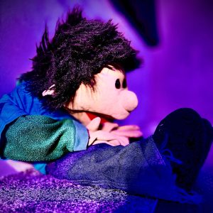 A puppet with spiky black hair dressed in blue